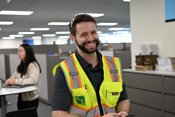 An S&C team member wearing a safety vest smiles for the camera