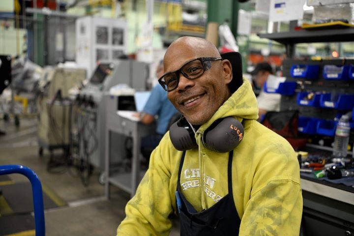 An S&C team member wearing personal protective equipment smiles at the camera An S&C team member wearing personal protective equipment smiles at the camera