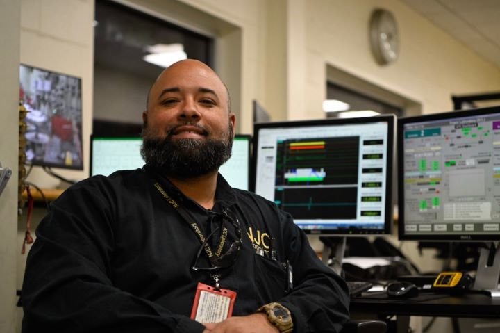 An S&C team member smiles in front of his computer