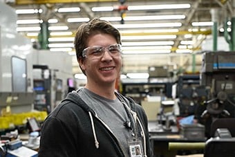 An S&C team member smiles while assembling an S&C product