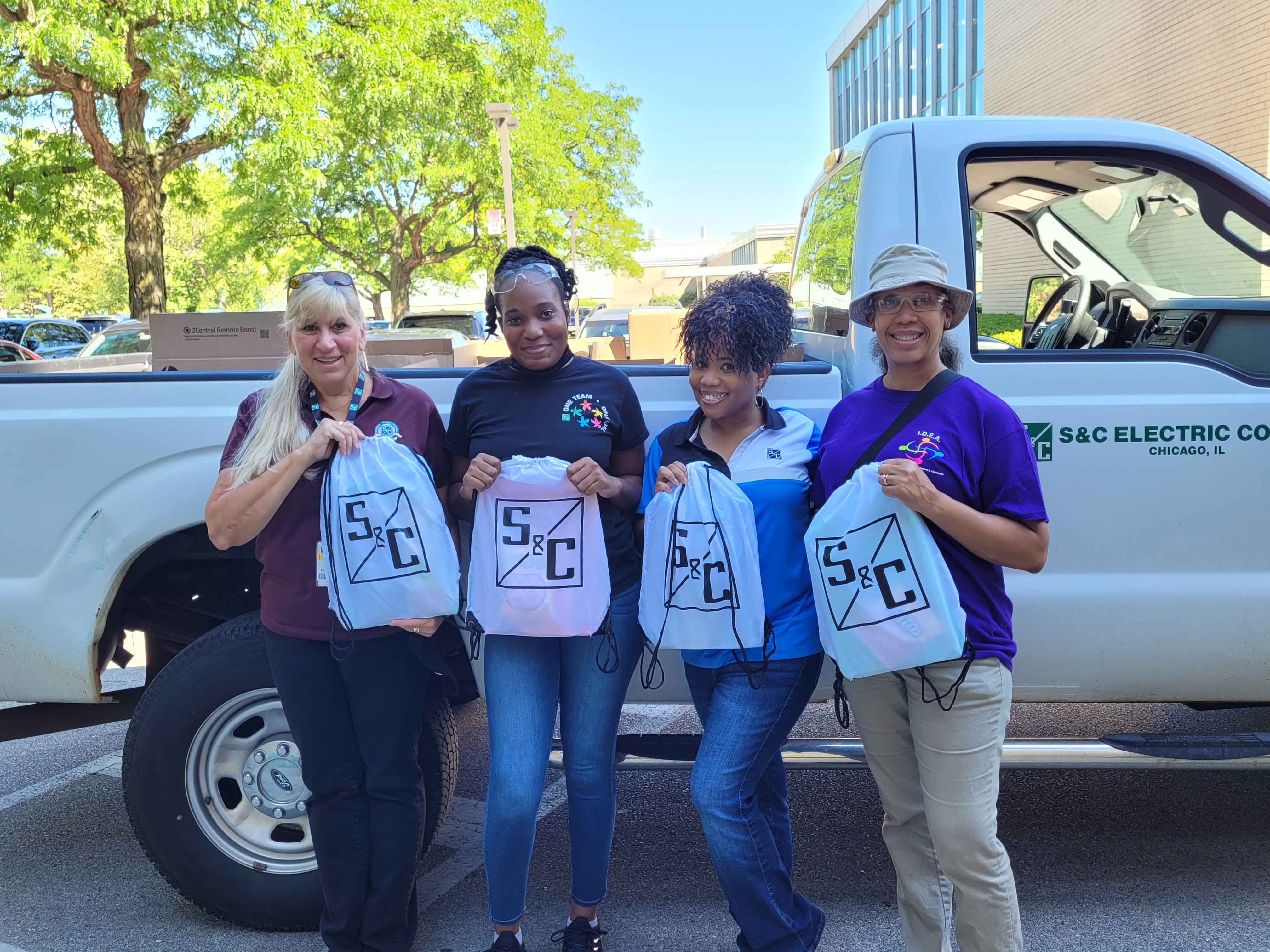 Four team members pose with donations for a local school Four team members pose with donations for a local school